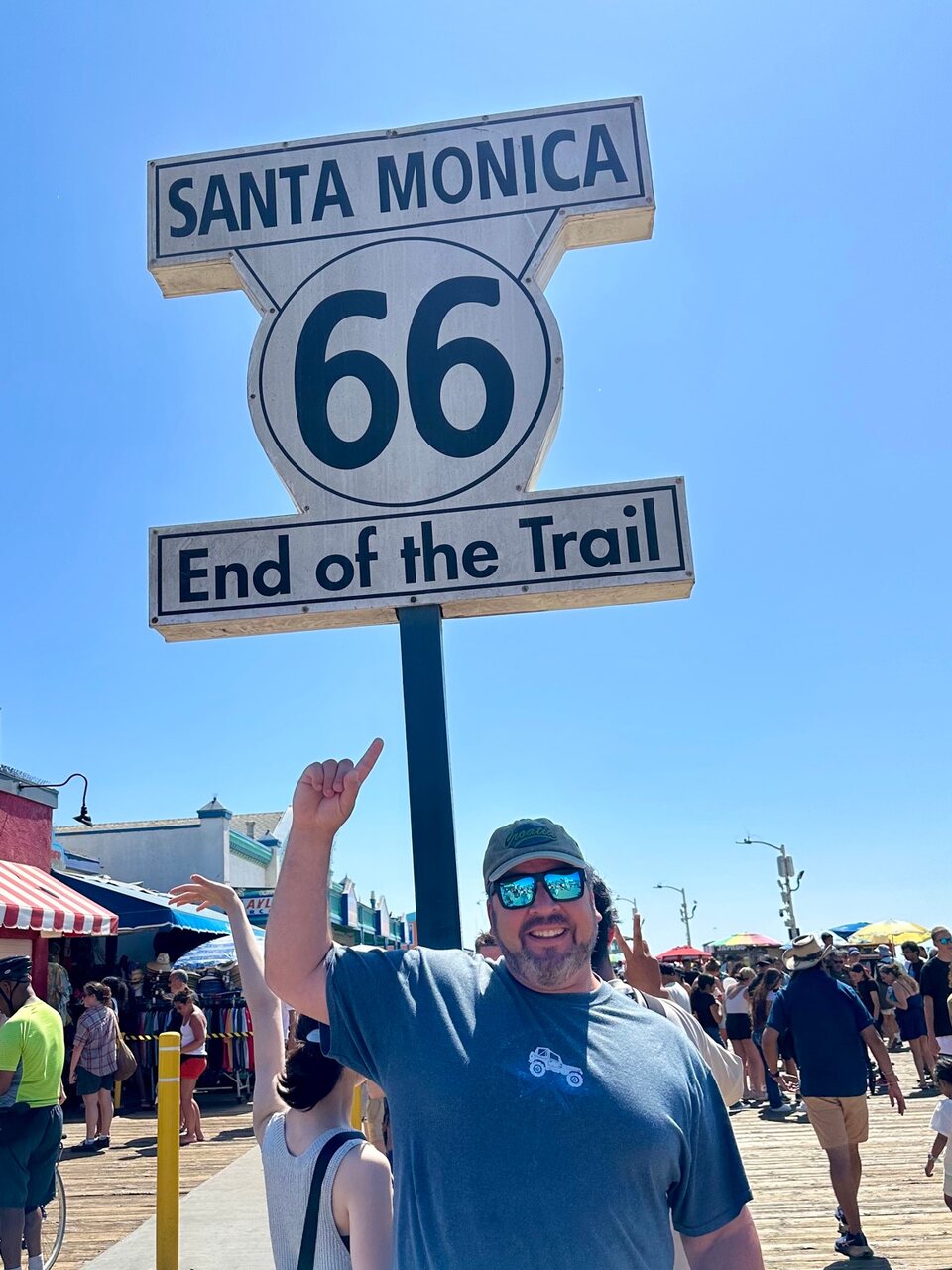 Traveler pointing up at the Route 66 End of the Trail sign in Santa Monica.