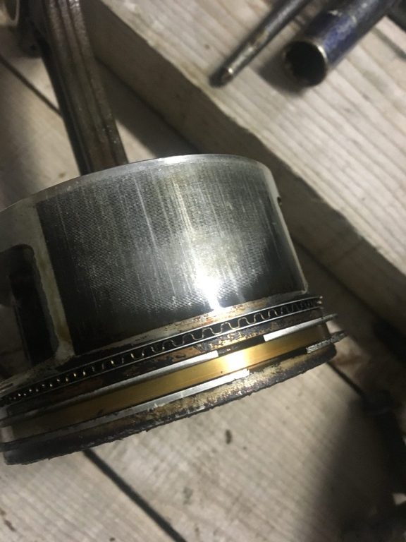 Close-up of a piston skirt and ring area, with surface marks visible on the metal.