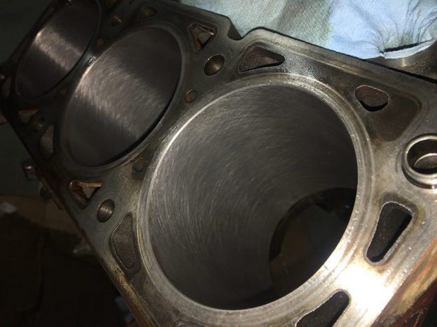 Close-up of open cylinder bores in the engine block, with surface marks visible on the cylinder walls.