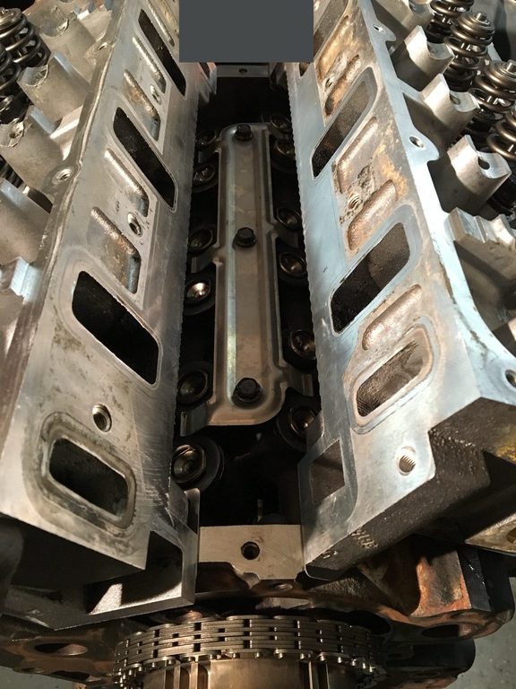 Close-up between the engine’s two cylinder heads, with intake openings and valve springs visible.
