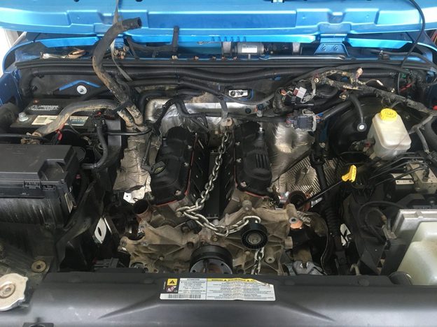 Front view of the V6 in the Jeep’s engine bay, with lifting chains and disconnected wiring visible.