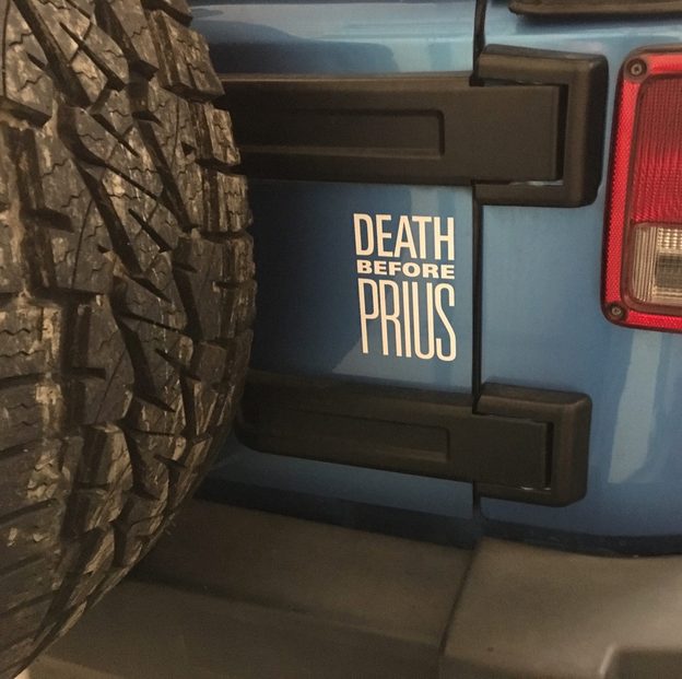 Blue Jeep tailgate with a white Death Before Prius decal beside the rear spare tire.